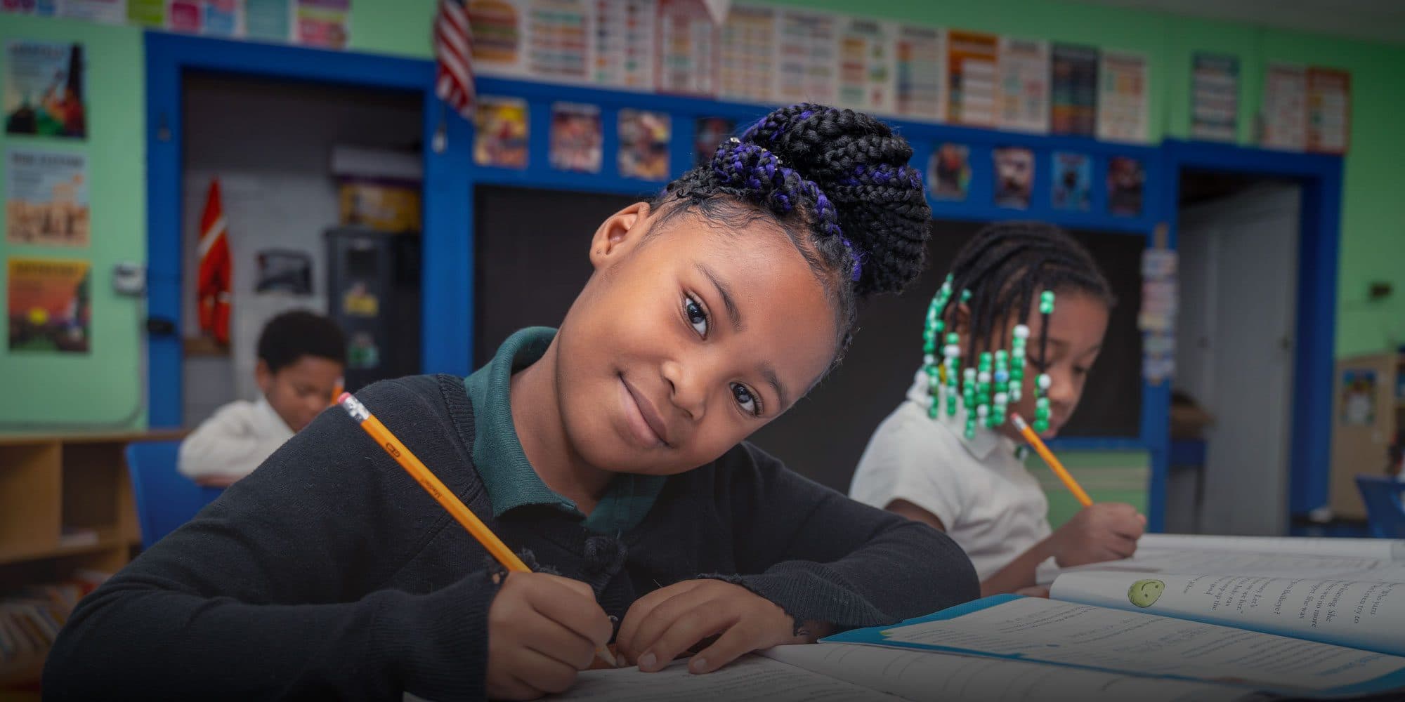 Student smiling while writing in a notebook during class.