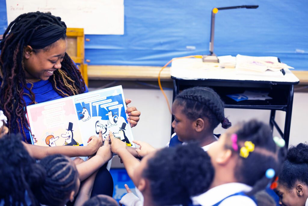Teacher reading to elementary students and students pointing out pictures in the book.